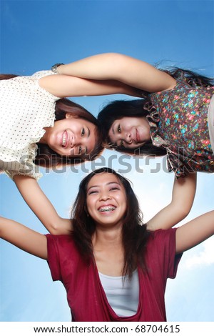 girls best friend hug each other under bright blue sky