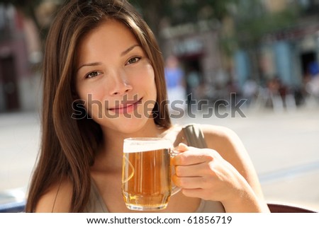 Beer woman enjoying a fresh draft beer outside on sidewalk cafe. Beautiful Caucasian / Asian model.