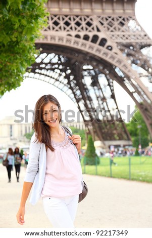 Paris woman by Eiffel Tower. Smiling young happy woman walking in front of the Eiffel Tower, Paris, France. Candid image.