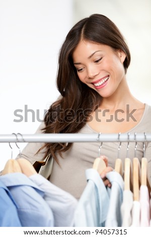 Shopping for clothing. Woman in clothes store. Shopper, small business owner or sales clerk smiling happy inside in shop. Multiracial young pretty woman.