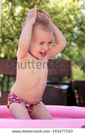 Baby playing in water in kiddie pool