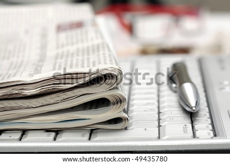 Newspapers and pen on notebook keyboard