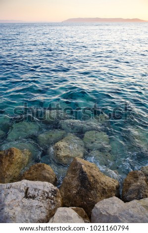 Popular travel destination for summer vacation travel.Beautiful sunset light on the beach.Crystal clear water washes rocky shore of Adriatic Sea in Croatia.Awesome sea scape view