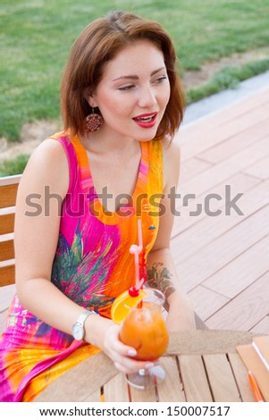 Beautiful young lady enjoying her fresh cocktail sitting in a restaurant outdoors