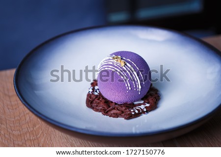 Decorative dessert food.Beautiful purple cake decorated with chocolate swarf served on round plate in Italian restaurant.Delicious desserts,pastry for snack meal.Enjoy desserts cooked in Italy