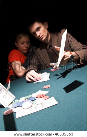Young man throwing money on the table while playing cards