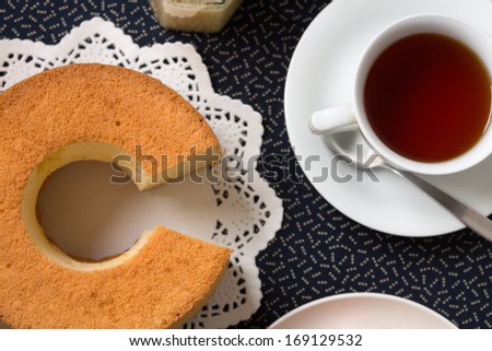 Circular-shaped chiffon cake with characteristic hole in the center from an ungreased tube pan. The cake is made with vegetable oil, eggs, sugar, flour, and flavorings. Served with a cup of black tea.