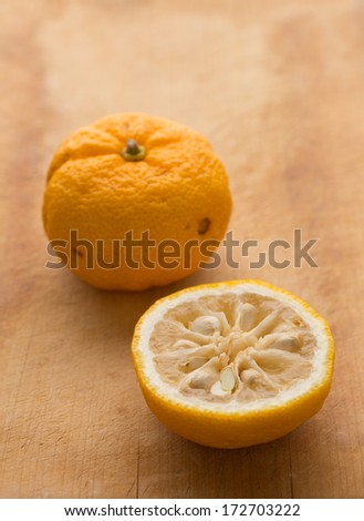 Halved and whole yuzu fruits on a cutting board. Yuzu is a hybrid between Citrus ichangensis and Citrus reticulata, famous for aromatic zest. Formerly know as Citrus junos.