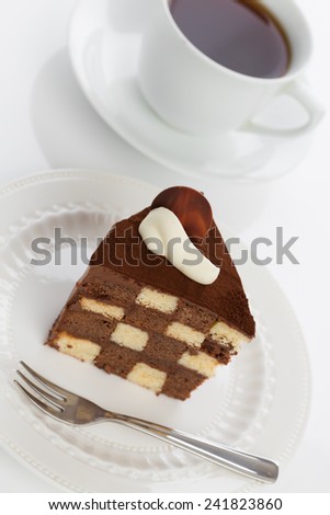 Vanilla and chocolate checkerboard cake makes a perfect tea time treat! The cake is garnished with whipped cream and cocoa powder, frosted with chocolate ganache. Shot with creative angle.