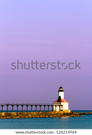 Lighthouse with its distinctive elevated catwalk at Michigan City, Indiana on Lake Michigan just after sunrise wit purple sky.
