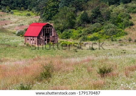 An old, weathered barn with a bright red roof stands in the hills of western Virginia.