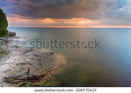 The risen sun shines rays through clouds over Lake Michigan at Door County, Wisconsin\'s Cave Point.