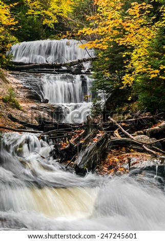 Sable Falls, a waterfall in Upper Peninsula Michigan\'s Pictured Rocks National Lakeshore, cascades through an autumn landscape of boulders and fallen trees.