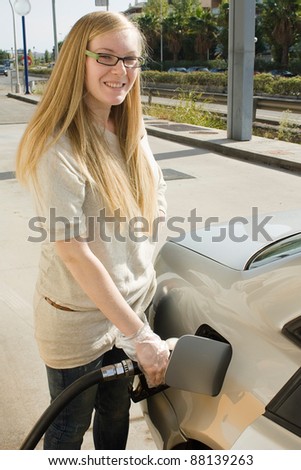 Woman holding fuel nozzle and refuel car in gas station.
