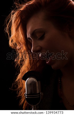 Singer in front of a old-fashion microphone on a black background