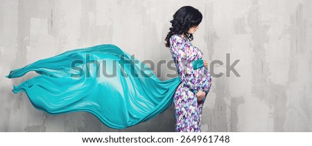 Pregnant woman with long hair over gray background