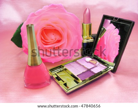 pink lipstick violet eye shadows and nail polisher on satin cloth background