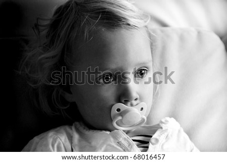 portrait of cute 2 year old girl uses her pacifier for comfort