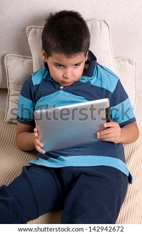 Cute boy playing game on tablet computer