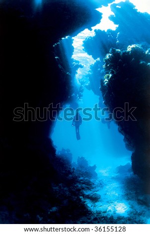Silhouette of a diver with sun rays through a cave