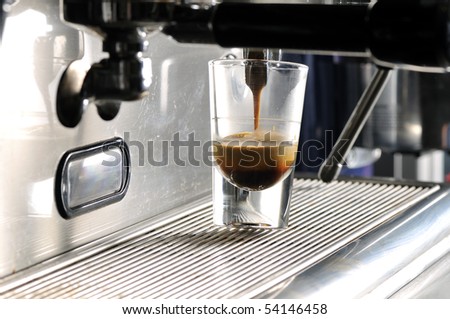 Coffee maker pouring hot espresso coffee in a cup.