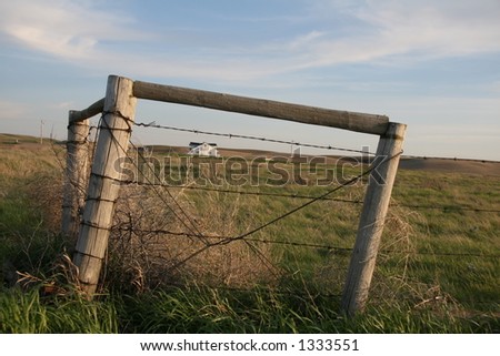 barbed wire fence corner posts framing ranch house
