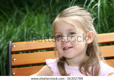 Adorable smile on this little girl\'s face with the sun shining on her cheek.