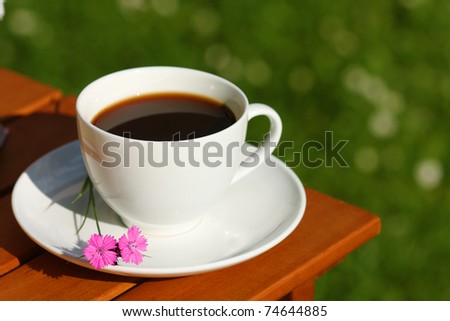 Drinking coffee in the garden. Black coffee in white cup