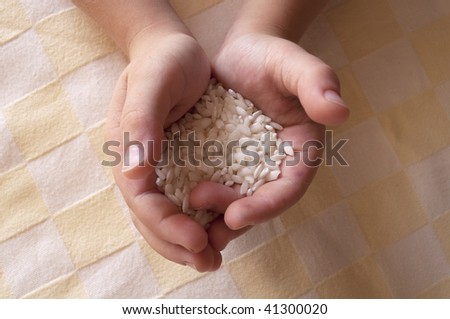 Handful of rice. Child\'s hands offering white rice.