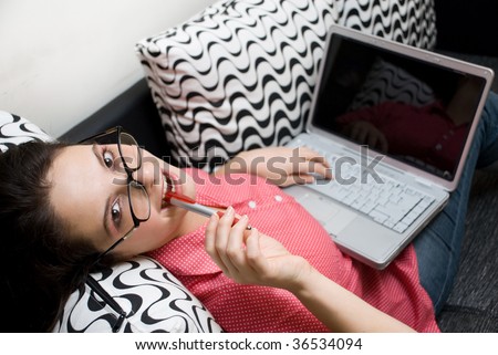 Woman wearing glasses with laptop sitting on couch
