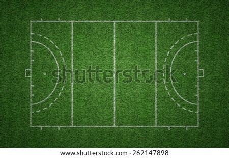 Green grass pitch of field hockey with white lines marking the pitch.