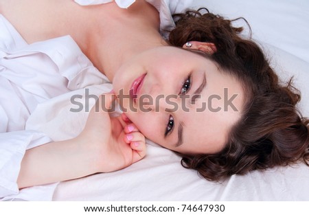 Young smiling woman lying on the white bed