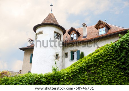 Castle like old mansion with round tower enclosed by a vine overgrown wall