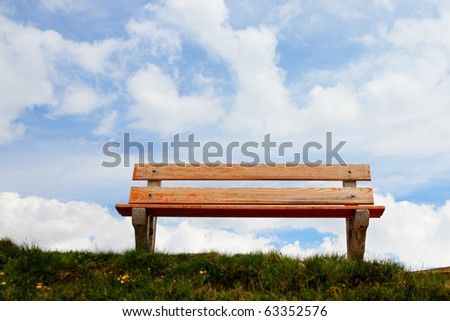 lone,empty wooden bench in front of a pretty blue sky, concept for a bench in heaven, a place to relax