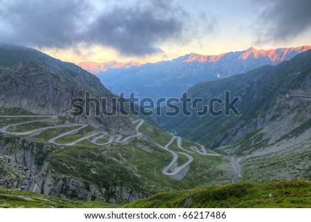 Old road with tight serpentines on the southern side of the St. Gotthard pass bridging swiss alps at sunset in Switzerland, europe