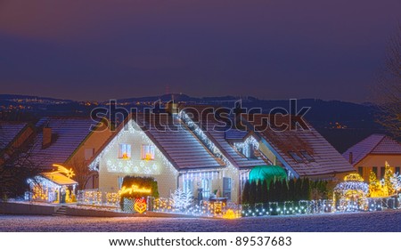 snowy houses at night fully decorated with christmas lights
