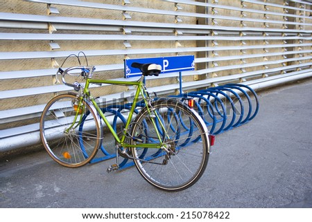 A bicycle parking in the parking lot against a wall