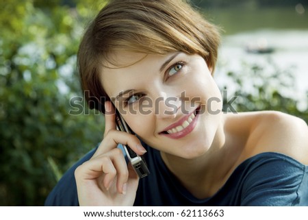 young woman talks outdoors with a cell phone in her hands