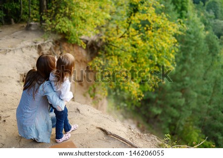 Little girl and her mother standing on the edge of a cliff