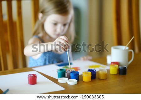 Cute little girl is drawing with paints in preschool