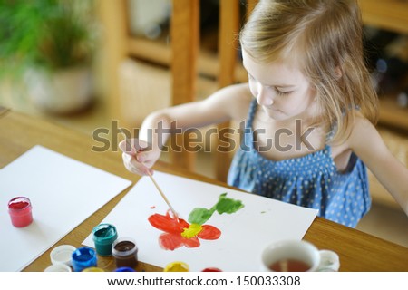 Cute little girl is drawing with paints in preschool