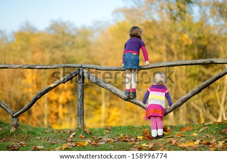 Two little sisters having fun in beautiful autumn park