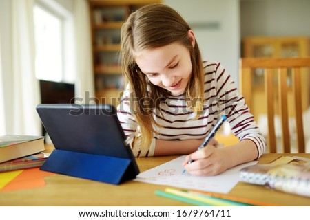 Preteen schoolgirl doing her homework with digital tablet at home. Child using gadgets to study. Education and distance learning for kids. Homeschooling during quarantine. Stay at home entertainment. Foto d'archivio © 