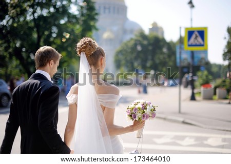 Happy bride and groom walking across the street
