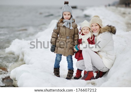 Young mother and her two daughters by the sea on winter