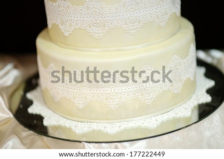 White wedding cake decorated with white lace and flowers