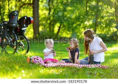 Young mother and her daughters picnicking in the park