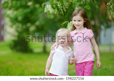 Two cute little sisters outdoors at summer