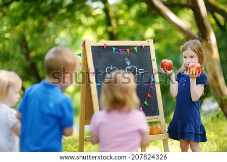 Adorable little girl playing a teacher standing by a blackboard in front of her little students