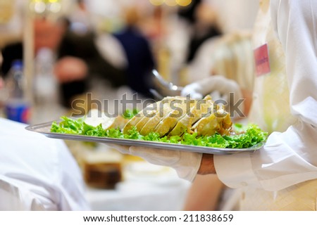 Waiter carrying a plate with delicious meat dish at party or reception